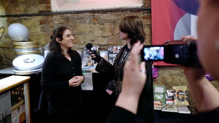 eine Person filmt, wie eine junge Person ein Interview mit einer Frau führt